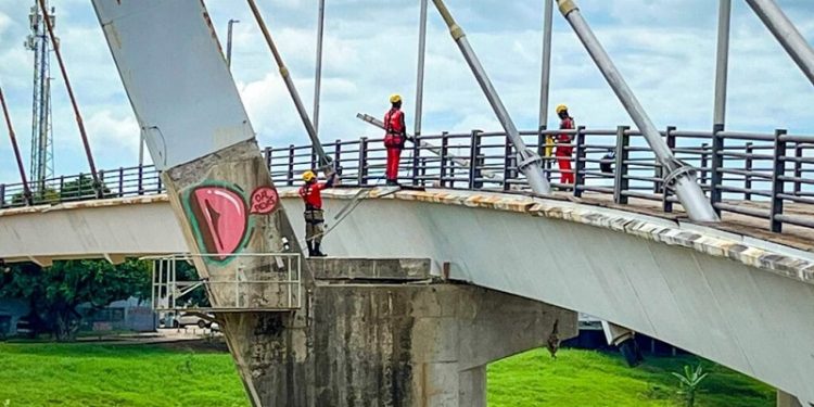 Instalação de cabos de aço é realizada no pilar principal da passarela Joaquim Macedo